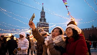 Tourists take a selfie in Red Square decorated for New Year celebrations, with the the Kremlin's Spasskaya Tower in the background, in Moscow, Russia.