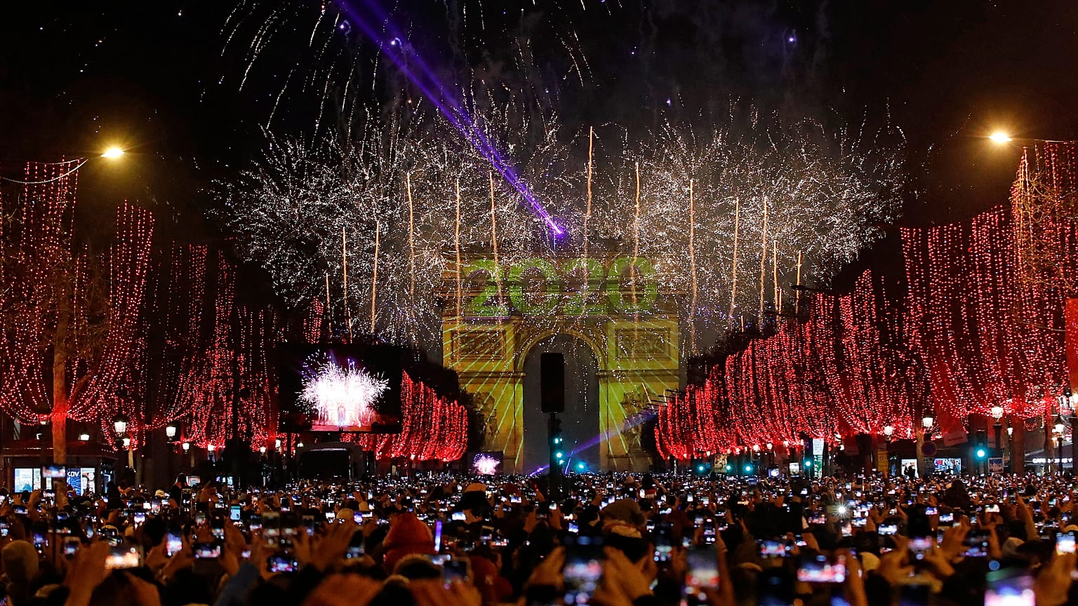 Revellers photograph fireworks over the Arc de Triomphe as they celebrate the New Year on the Champs Elysees, in Paris, France, Wednesday, Jan. 1, 2020.