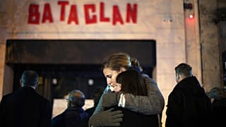 In this Nov. 13, 2016 file photo, women hug in front of the Bataclan concert hall in Paris, as France marked the anniversary of Islamic extremists' coordinated attacks.