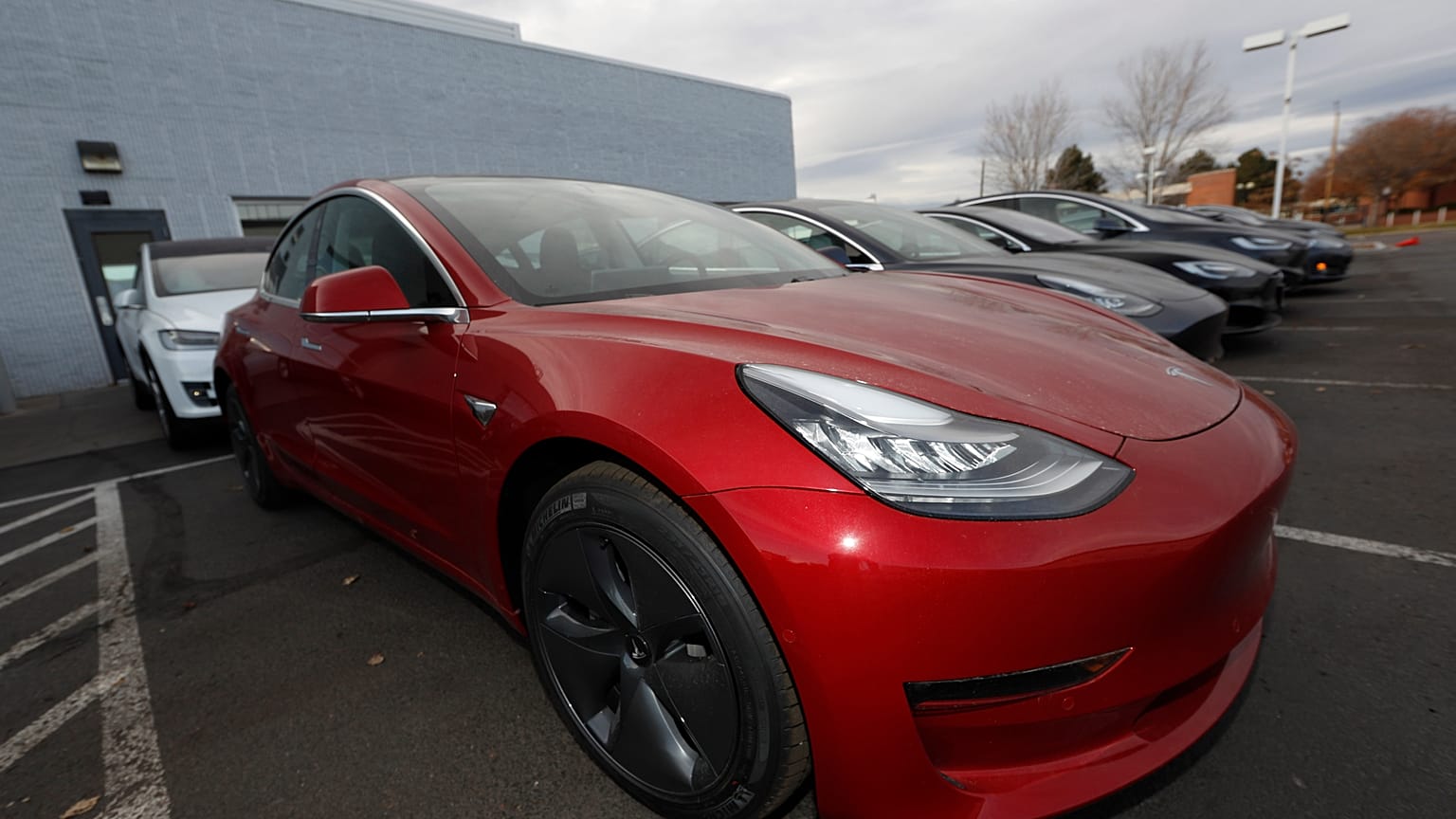 In this Sunday, Nov. 10, 2019, photograph, a long row of unsold 2020 Model 3 sedans sits at a Tesla dealership in Littleton, Colo. (AP Photo/David Zalubowski)