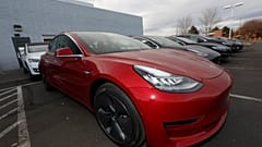 In this Sunday, Nov. 10, 2019, photograph, a long row of unsold 2020 Model 3 sedans sits at a Tesla dealership in Littleton, Colo. (AP Photo/David Zalubowski)