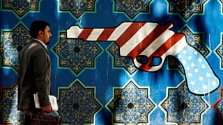 An Iranian man walks pass an anti-U.S. graffiti painted on the wall of the former U.S. Embassy in Tehran