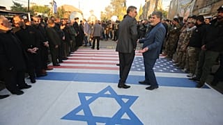 Iraqi paramilitaries walk on pictures Trump and Netanyahu