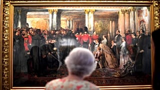 Queen Elizabeth II looks at a painting of Queen Victoria