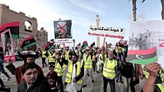 In this April 19, 2019 file photo, protesters wear yellow vests at a protest as they wave national flags and chant slogans against Libya's Field Marshal Khalifa Hafter