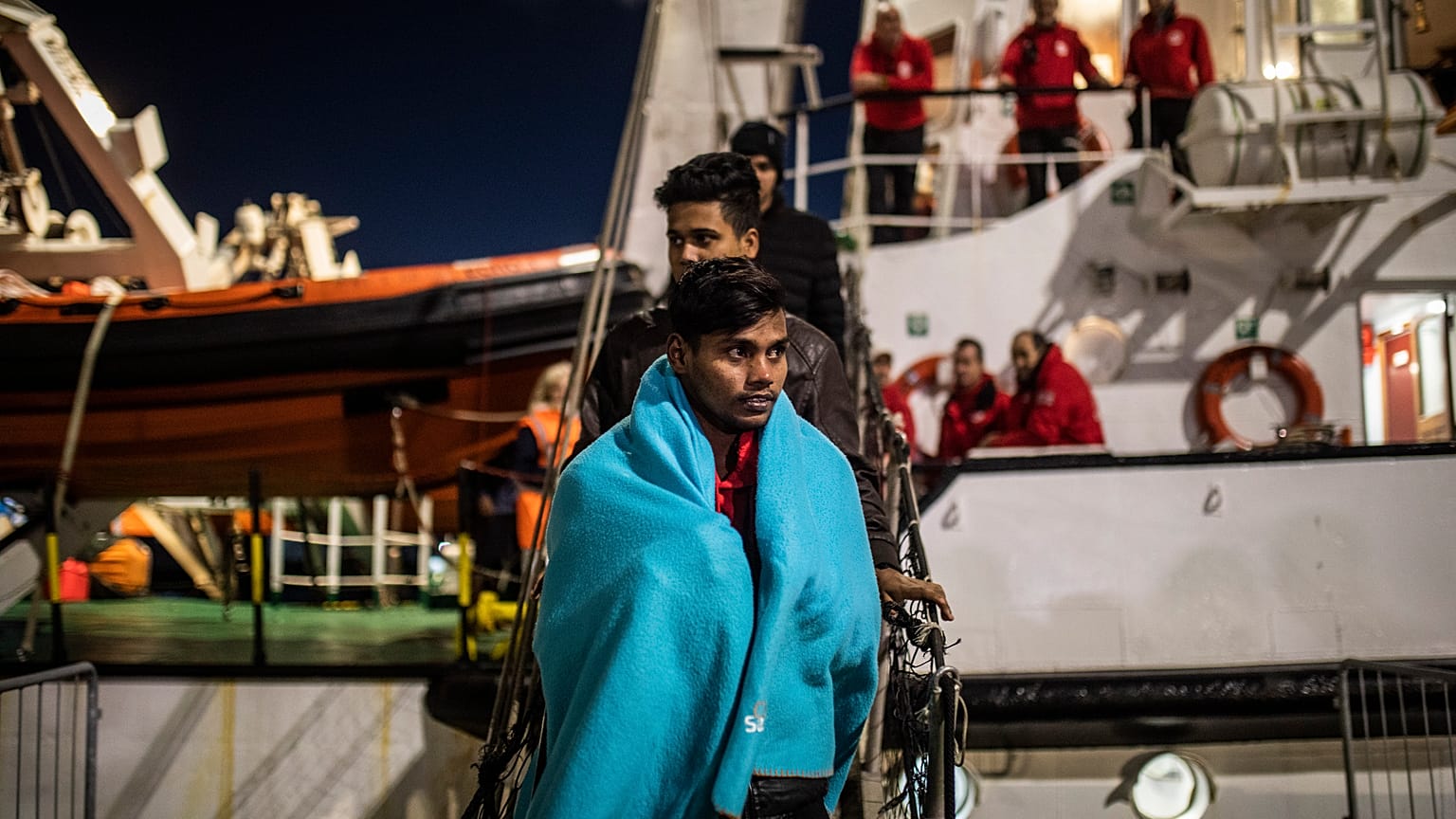 Migrantes de Bangladesh desembarcan del buque de rescate Open Arms en el puerto de Messina después de ser rescatados el viernes frente a la costa de Libia, en Sicilia, Italia