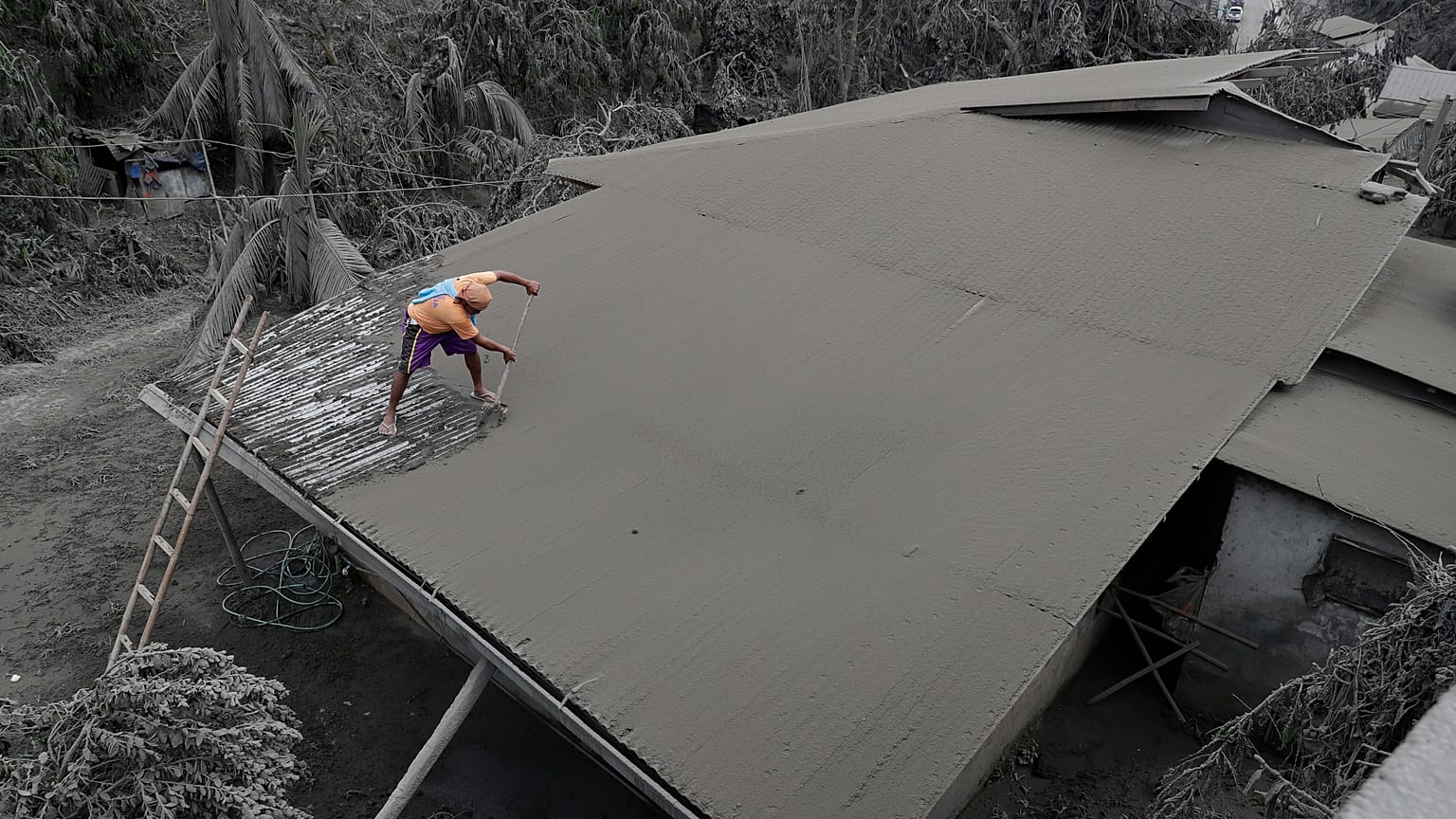 A resident clears volcanic ash from his roof in Laurel, Batangas province, the southern Philippines on Tuesday, 14 January, 2020
