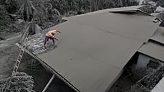 A resident clears volcanic ash from his roof in Laurel, Batangas province, the southern Philippines on Tuesday, 14 January, 2020
