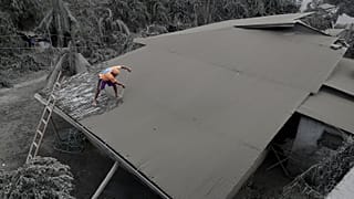 A resident clears volcanic ash from his roof in Laurel, Batangas province, the southern Philippines on Tuesday, 14 January, 2020