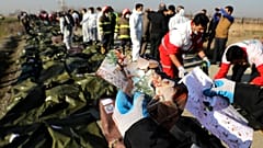 أحد عمال الإنقاذ يحمل صورا وجدت في موقع تحطم الطائرة الأوكرانية في طهران - إيران