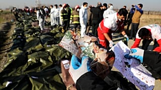 أحد عمال الإنقاذ يحمل صورا وجدت في موقع تحطم الطائرة الأوكرانية في طهران - إيران