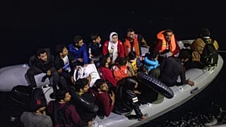 Refugees and migrants on a plastic boat approach a Greek Coast Guard ship in September 2019