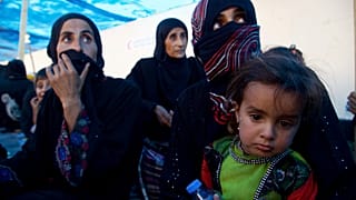 صورة للمشردين من النساء والأطفال يجلسون على الأرض عند نقطة تجميع غرب الموصل