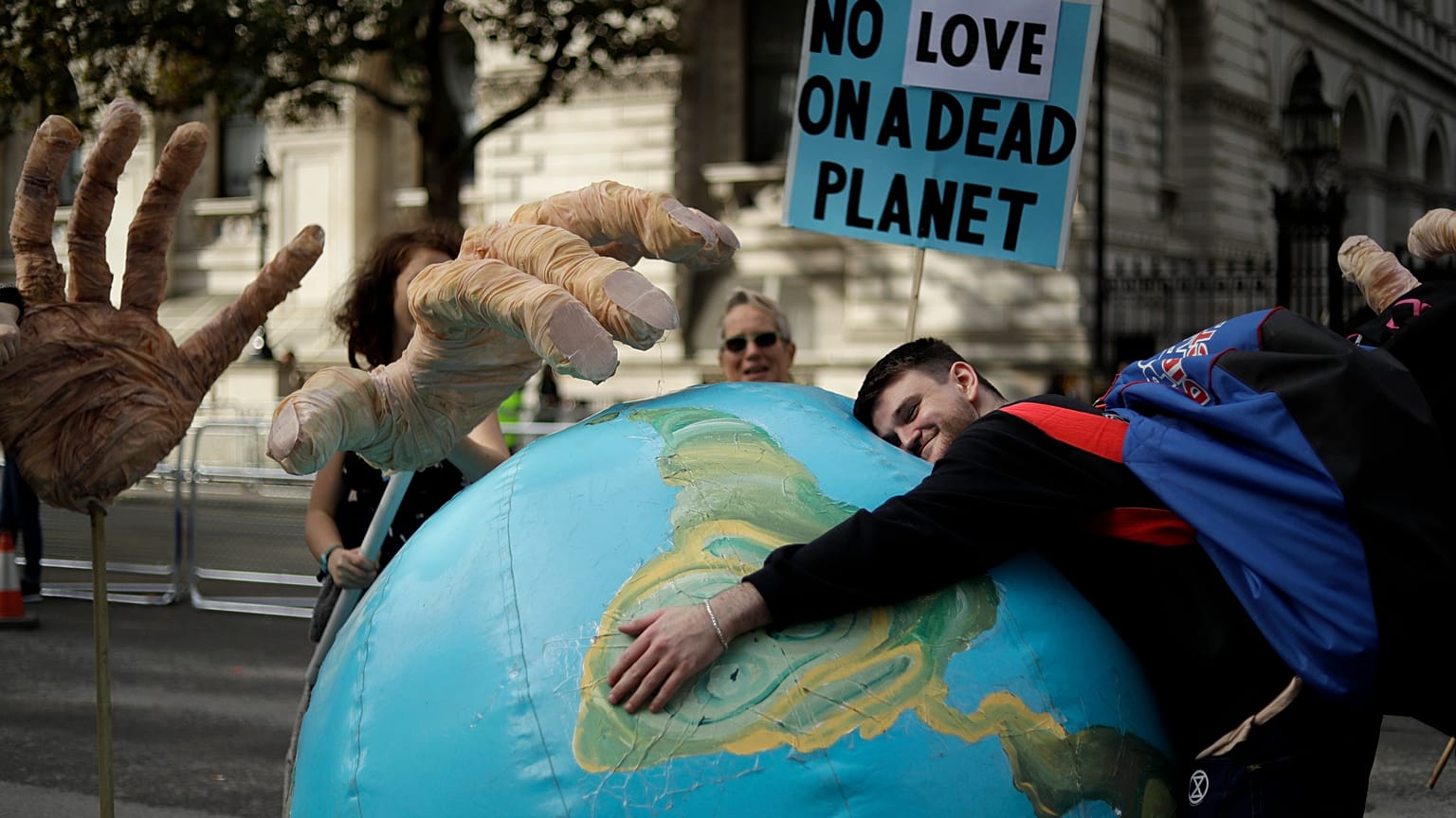 An Extinction Rebellion climate change protester hugs an inflatable planet Earth near Downing Street in London.