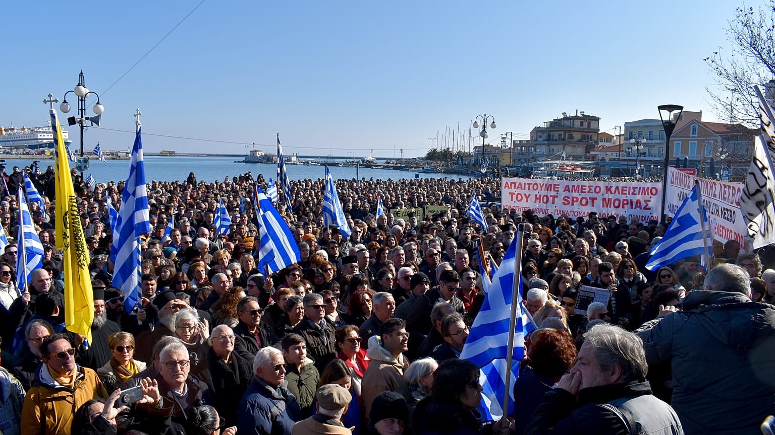 Κόσμος κρατώντας σημαίες και πανό συμμετέχει στη συγκέντρωση διαμαρτυρίας για το μεταναστευτικό