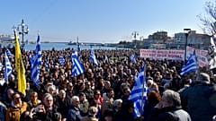 Κόσμος κρατώντας σημαίες και πανό συμμετέχει στη συγκέντρωση διαμαρτυρίας για το μεταναστευτικό