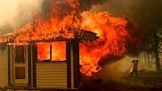 A firefighter battles the Morton Fire as it consumes a home near Bundanoon, New South Wales, Australia. January 23 2020