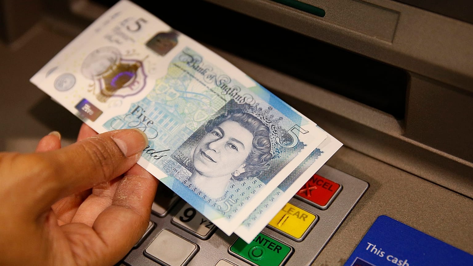 A member of staff at a branch of Halifax bank, in London, displays a new British 5 pound sterling note