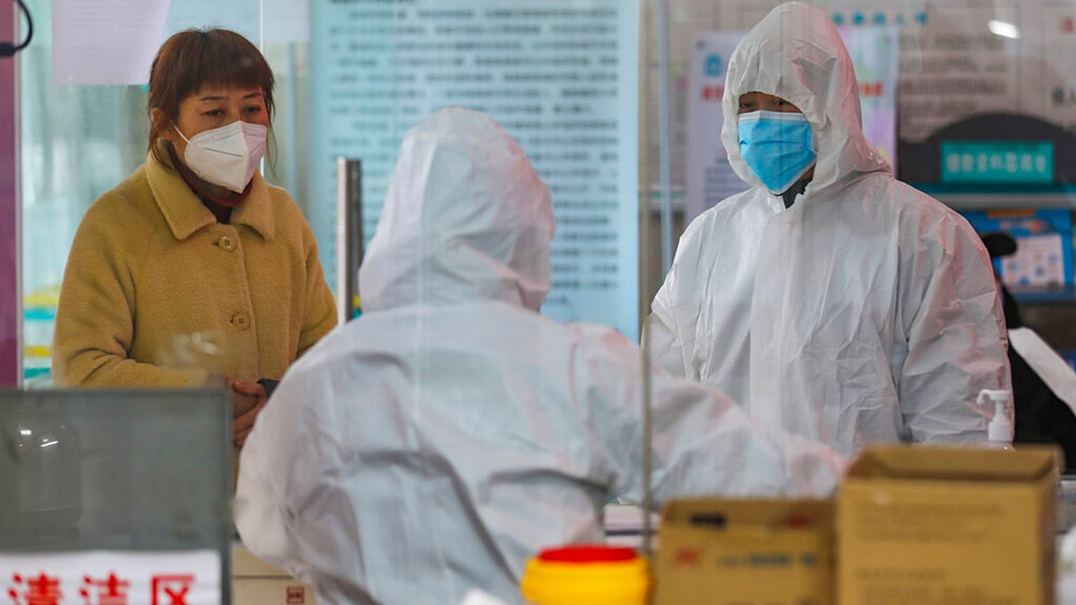 Medical workers in protective gear talk with a woman suspected of being ill with a coronavirus at a community health station in Wuhan in central China's Hubei Province