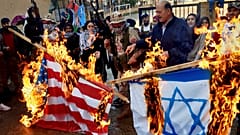 فلسطينيون مسلحون ومدنيون يحرقون علمي إسرائيل والولايات المتحدة خلال احتجاج في مخيم عين الحلوة في لبنان 