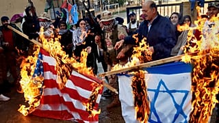 فلسطينيون مسلحون ومدنيون يحرقون علمي إسرائيل والولايات المتحدة خلال احتجاج في مخيم عين الحلوة في لبنان 