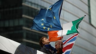 Two anti-Brexit people hold EU, Ireland and Union Flags stand outside the European Commission in Brussels, Friday, Oct. 11, 2019
