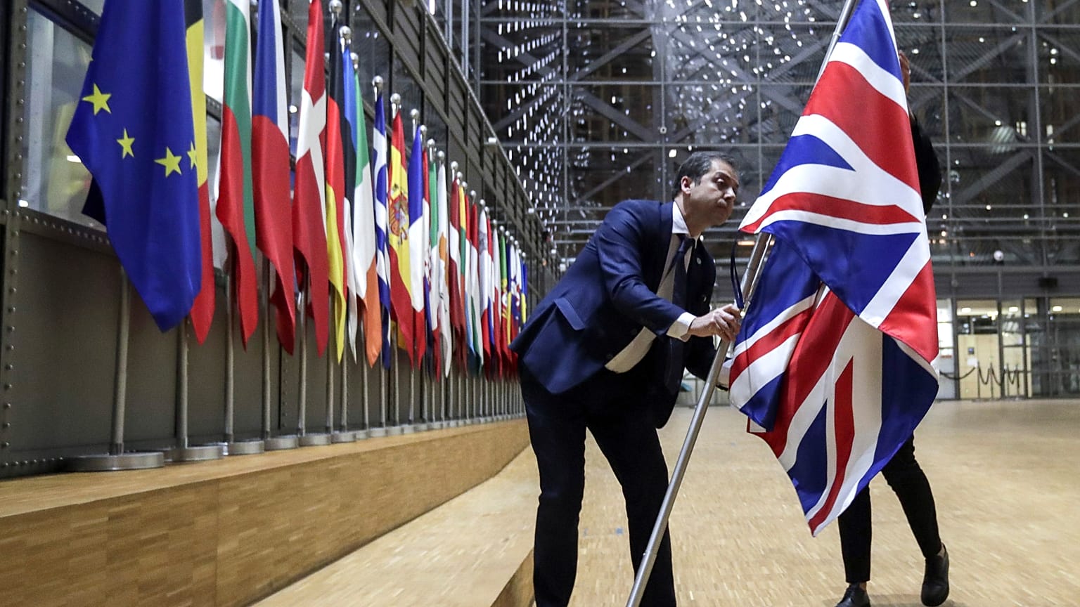 A member of protocol removes the Union flag from the atrium of the Europa building in Brussels, Friday, Jan. 31, 2020.