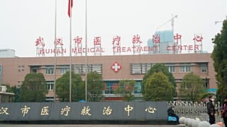People stand outside the Wuhan Medical Treatment Center, where some infected with a novel coronavirus are being treated, in Wuhan, China, Tuesday, Jan. 21, 2020