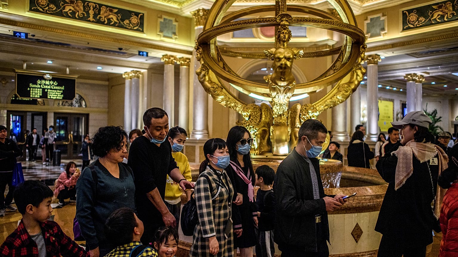 This file photo taken on January 22, 2020 shows visitors wearing face masks as they walk inside the Venetian casino hotel resort in Macau.