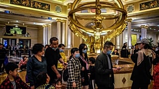 This file photo taken on January 22, 2020 shows visitors wearing face masks as they walk inside the Venetian casino hotel resort in Macau.