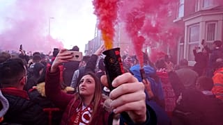 Football supporters set off flares before the English Premier League soccer match between Liverpool and Manchester United near Anfield Stadium in Liverpool.