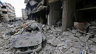 People inspect a damaged site after airstrikes on the town of Ariha, in Idlib province