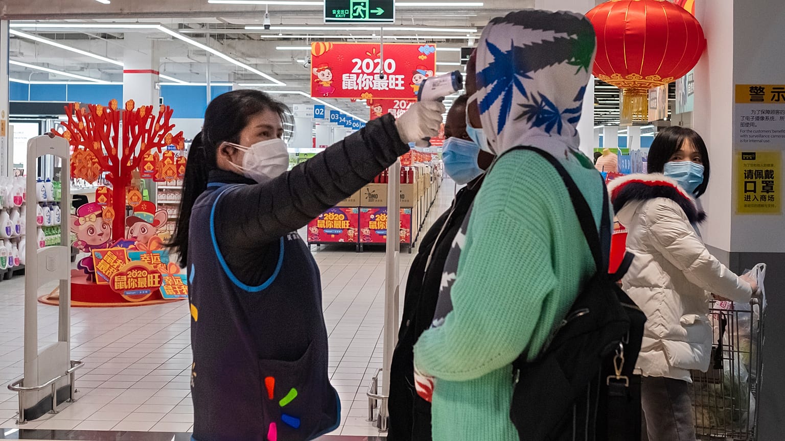 A worker takes the temperature of a customer at the entrance of a Walmart store in Wuhan in central China's Hubei Province