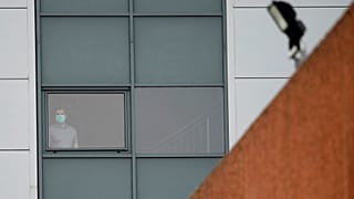 An person wearing a mask stands at a window of a staff accomodation block at Arrowe Park Hospital on the Wirral.