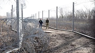 FILE: A Hungarian policeman and a military personnel patrol at the border station between Roszke, Hungary, and Horgos, Serbia, Wednesday, Jan. 29, 2020