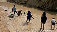 FILE - In this March 31, 2019 file photo, children play in a mud puddle in the section for foreign families at Al-Hol camp in Hasakeh province, Syria.