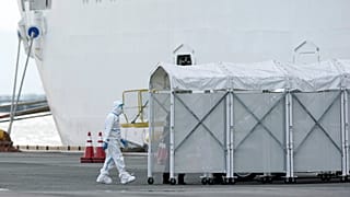 Bir yetkili korunma kıyafeti ile Japonya'nın Yokohama Limanı'nda karantinaya alınan  Diamond Princess gemisine giriyor