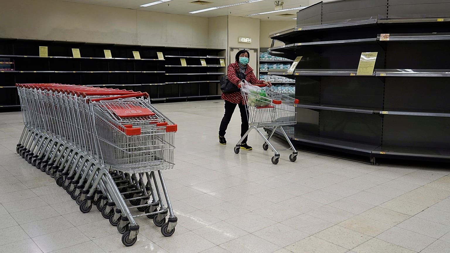 A woman wearing face mask, walks past empty shelf of tissue papers at supermarket  in Hong Kong, Friday, Feb. 7, 2020