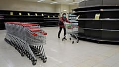 A woman wearing face mask, walks past empty shelf of tissue papers at supermarket  in Hong Kong, Friday, Feb. 7, 2020