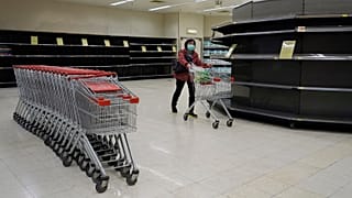 A woman wearing face mask, walks past empty shelf of tissue papers at supermarket  in Hong Kong, Friday, Feb. 7, 2020