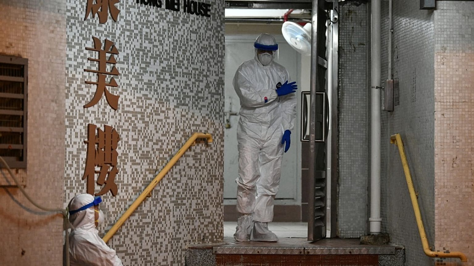 Medical personnels wearing protective suits wait near a block's entrance in the ground of a residential estate, in Hong Kong, on February 11, 2020