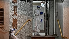 Medical personnels wearing protective suits wait near a block's entrance in the ground of a residential estate, in Hong Kong, on February 11, 2020