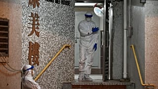 Medical personnels wearing protective suits wait near a block's entrance in the ground of a residential estate, in Hong Kong, on February 11, 2020