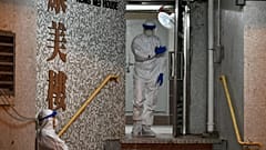 Medical personnels wearing protective suits wait near a block's entrance in the ground of a residential estate, in Hong Kong, on February 11, 2020