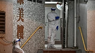 Medical personnels wearing protective suits wait near a block's entrance in the ground of a residential estate, in Hong Kong, on February 11, 2020