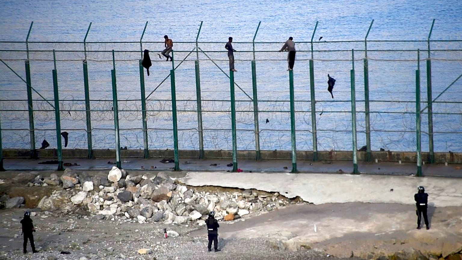 Migrants climb a fence that divides Morocco and Ceuta in this 2019 file photo 