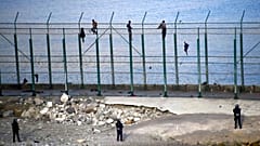 Migrants climb a fence that divides Morocco and Ceuta in this 2019 file photo 