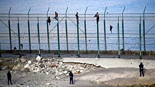Migrants climb a fence that divides Morocco and Ceuta in this 2019 file photo 
