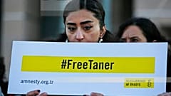 Human rights activists hold placards demanding the release of Amnesty's Turkey chairman Taner Kilic