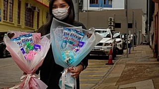 Flower shop owner Iris Leung wears her protective face mask as she delivers flowers with masks to customers on Valentine's Day in Hong Kong, Friday, Feb. 14, 2020.